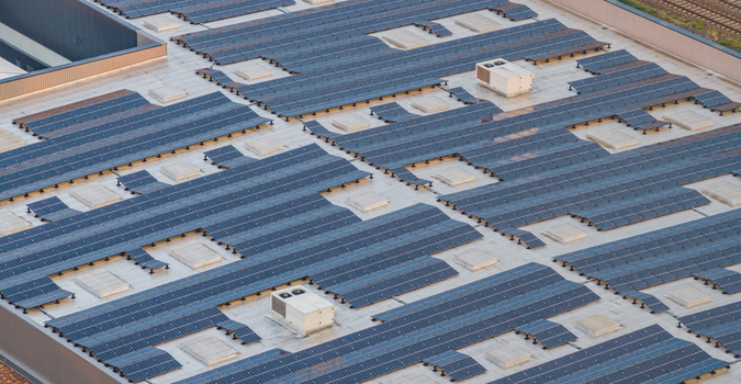 Aerial view of industrial rooftop solar panels and HVAC systems on a modern logistics warehouse Alixan Auvergne Rhone Alpes France.