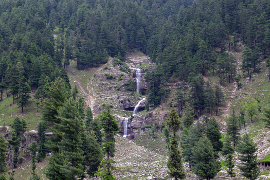 View of the waterfall cascading down a rocky cliff surrounded by dense pine forests in Kumrat Valley Khyber Pakhtunkhwa Pakistan. View of the waterfall cascading down a rocky cliff surrounded by dense pine forests in Kumrat Valley Khyber Pakhtunkhwa Pakistan.