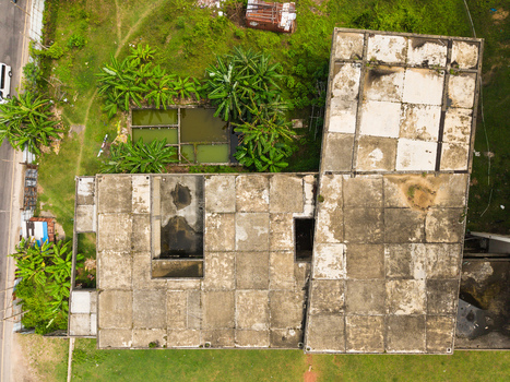 Aerial view of a weathered concrete building roof with a grid pattern surrounded by lush tropical greenery and small ponds in Galle Southern Province Sri Lanka. Aerial view of a weathered concrete building roof with a grid pattern surrounded by lush tropical greenery and small ponds in Galle Southern Province Sri Lanka.