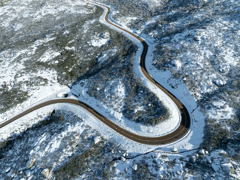 Aerial view of a winding road cutting through the snow dusted landscape a ribbon of dark asphalt against the brilliant white São Romão Guarda District Portugal. Aerial view of a winding road cutting through the snow dusted landscape a ribbon of dark asphalt against the brilliant white São Romão Guarda District Portugal.