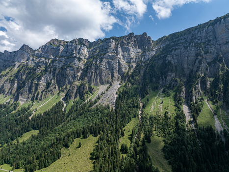 Aerial view of the rugged limestone cliffs of the Niederhorn mountain range overlooking the lush green slopes and forests of the Justistal valley in Sigriswil Bern Switzerland. Aerial view of the rugged limestone cliffs of the Niederhorn mountain range overlooking the lush green slopes and forests of the Justistal valley in Sigriswil Bern Switzerland.