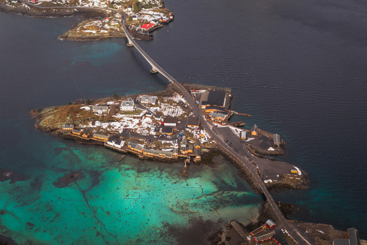 Aerial view of a bridge connecting islands reflecting the turquoise waters below with snow dusted buildings adding contrast Sakris&oslash;ya Nordland Norway.
