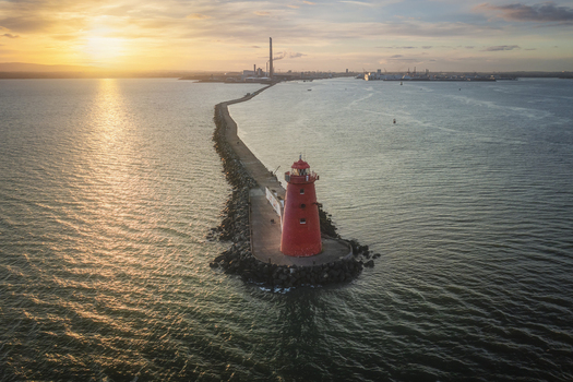 Aerial view of the red Poolbeg Lighthouse at the end of the Great South Wall pier during a golden sunset over Dublin Bay Dublin County Dublin Ireland.