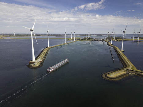 Aerial view of Grevelingendam wind farm with a cargo ship navigating the waterway surrounded by calm water and blue sky in Bruinisse Zeeland Netherlands. Aerial view of Grevelingendam wind farm with a cargo ship navigating the waterway surrounded by calm water and blue sky in Bruinisse Zeeland Netherlands.