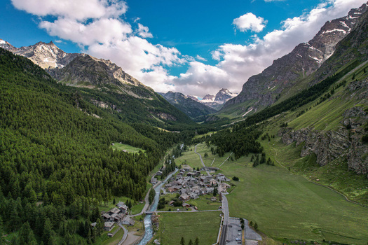 Aerial view of the village of Rhemes Notre Dame nestled in a deep mountain valley surrounded by pine forests and high peaks Rhemes Notre Dame Valle d Aosta Italy. Aerial view of the village of Rhemes Notre Dame nestled in a deep mountain valley surrounded by pine forests and high peaks Rhemes Notre Dame Valle d Aosta Italy.