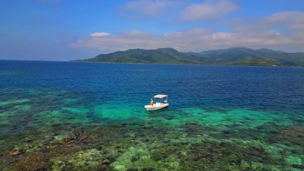 Aerial view of a boat on turquoise water near the coast of Honduras.