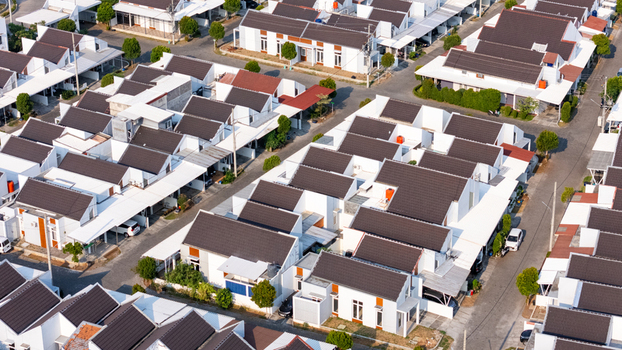 Aerial view of a modern residential housing complex with white houses dark roofs and paved streets in Semarang Central Java Indonesia.