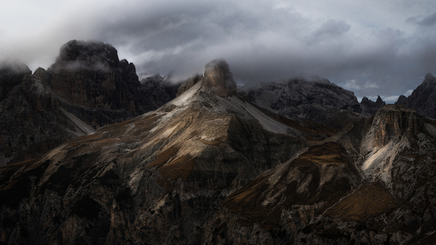 View of Dolomites mountain peaks shrouded in dark clouds and dramatic shadows Trentino Alto Adige Italy. View of Dolomites mountain peaks shrouded in dark clouds and dramatic shadows Trentino Alto Adige Italy.