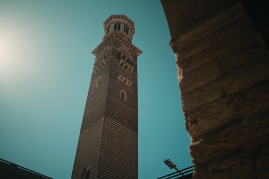 View of the historic Torre dei Lamberti medieval bell tower rising into a clear blue sky from a low angle perspective in Verona Veneto Italy.