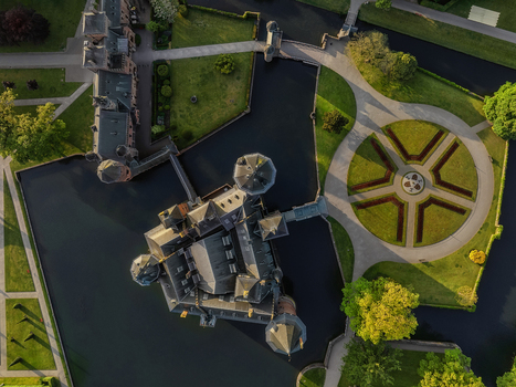 Aerial view of De Haar Castle featuring its Gothic towers dark moat water and symmetrical circular garden patterns in Utrecht Utrecht Netherlands. Aerial view of De Haar Castle featuring its Gothic towers dark moat water and symmetrical circular garden patterns in Utrecht Utrecht Netherlands.