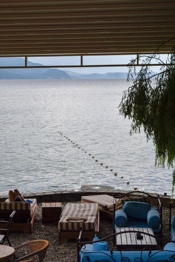 View of a lounge area with sunbeds and chairs overlooking the calm waters of Lake Ohrid in Ohrid Municipality of Ohrid North Macedonia. View of a lounge area with sunbeds and chairs overlooking the calm waters of Lake Ohrid in Ohrid Municipality of Ohrid North Macedonia.