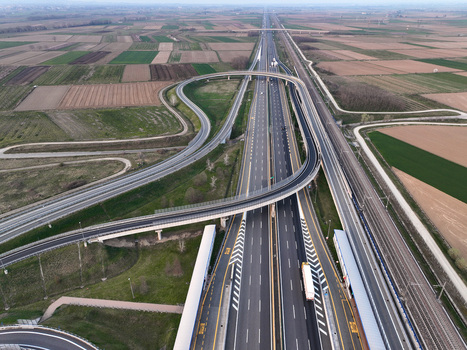 Aerial view of the A4 Torino Milano motorway interchange with curved overpasses surrounding agricultural fields and a parallel railway line under a clear sky in Borgo d Ale Piedmont Italy. Aerial view of the A4 Torino Milano motorway interchange with curved overpasses surrounding agricultural fields and a parallel railway line under a clear sky in Borgo d Ale Piedmont Italy.