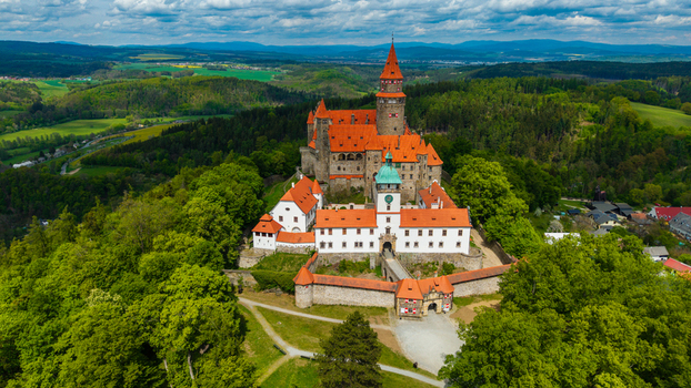 Aerial view of Bouzov Castle with its iconic red tiled roofs and tall stone tower nestled among lush green forests and rolling hills in Bouzov Olomoucky kraj Czechia. Aerial view of Bouzov Castle with its iconic red tiled roofs and tall stone tower nestled among lush green forests and rolling hills in Bouzov Olomoucky kraj Czechia.