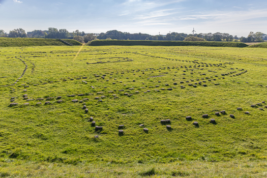 View of the Viking Fortress Trelleborg with stone foundations visible in a grassy field surrounded by earth ramparts under a clear blue sky in Slagelse Sjaelland Denmark. View of the Viking Fortress Trelleborg with stone foundations visible in a grassy field surrounded by earth ramparts under a clear blue sky in Slagelse Sjaelland Denmark.