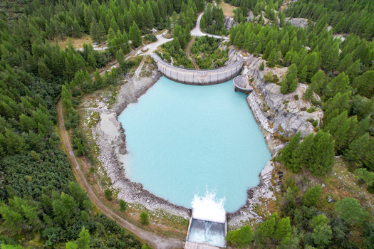 Aerial view of Barrage de Ferpecle with its turquoise reservoir surrounded by dense pine forests and rocky terrain in Evolene Valais Switzerland. Aerial view of Barrage de Ferpecle with its turquoise reservoir surrounded by dense pine forests and rocky terrain in Evolene Valais Switzerland.
