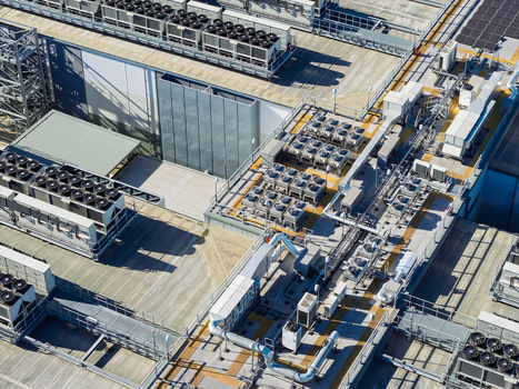 Aerial view of a data center roof featuring rows of industrial HVAC cooling units ventilation pipes and technical infrastructure in the United Kingdom.