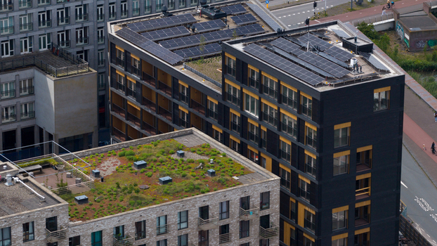 Aerial view of modern sustainable apartment buildings featuring solar panels and lush green rooftop gardens under bright daylight Amsterdam North Holland Netherlands. Aerial view of modern sustainable apartment buildings featuring solar panels and lush green rooftop gardens under bright daylight Amsterdam North Holland Netherlands.