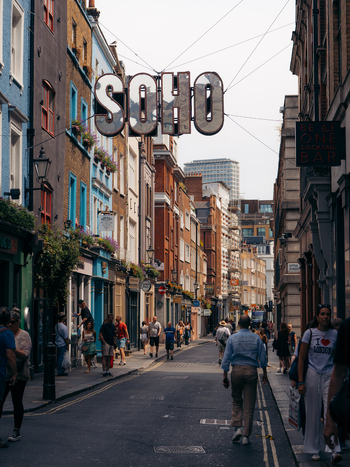 London United Kingdom 20 June 2025 View of the vibrant Soho street teeming with pedestrians amidst colorful buildings and the iconic SOHO sign overhead. London United Kingdom 20 June 2025 View of the vibrant Soho street teeming with pedestrians amidst colorful buildings and the iconic SOHO sign overhead.