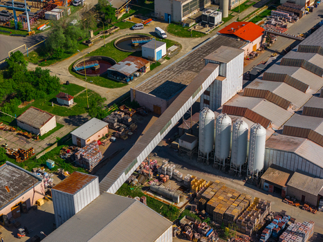 Aerial view of an industrial facility featuring white silos a long conveyor bridge and circular treatment tanks in Kyjov South Moravian Region Czechia.