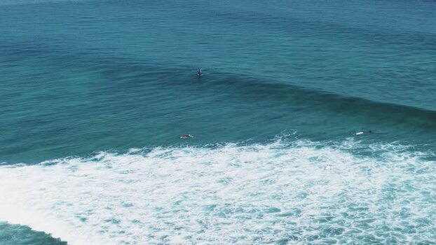 Aerial view of surfers in the turquoise ocean Maldives.
