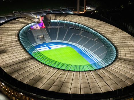 Berlin Germany 26 September 2026 Aerial view of Olympiastadion Berlin at night featuring the illuminated stadium roof the vibrant green pitch and the blue running track.