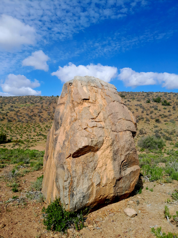 View of a large weathered boulder standing in the semi arid landscape of Anysberg Nature Reserve under a bright blue sky with scattered clouds Anysberg Western Cape South Africa. View of a large weathered boulder standing in the semi arid landscape of Anysberg Nature Reserve under a bright blue sky with scattered clouds Anysberg Western Cape South Africa.