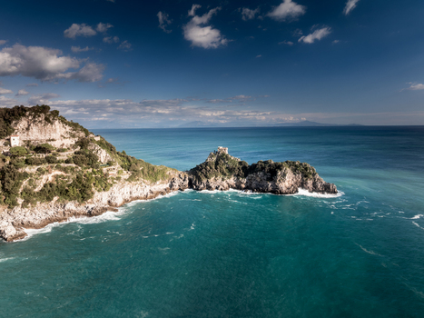 Aerial view of a rocky promontory with an ancient fortress juts into the turquoise sea under a vast sky Amalfi Campania Italy. Aerial view of a rocky promontory with an ancient fortress juts into the turquoise sea under a vast sky Amalfi Campania Italy.