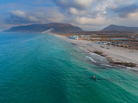 Aerial view of turquoise waters meet the sandy shore under a vast sky with buildings nestled near the coast Ararhin Socotra Yemen. Aerial view of turquoise waters meet the sandy shore under a vast sky with buildings nestled near the coast Ararhin Socotra Yemen.