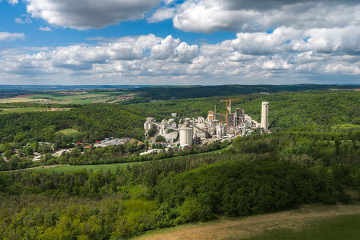Aerial view of a large cement factory complex nestled among lush green forests and rolling hills under a bright cloudy sky Mokra Horakov Jihomoravsky kraj Czechia. Aerial view of a large cement factory complex nestled among lush green forests and rolling hills under a bright cloudy sky Mokra Horakov Jihomoravsky kraj Czechia.