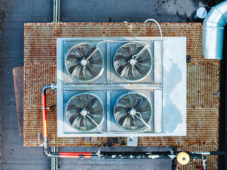 Aerial view of an industrial HVAC unit with four large fans mounted on a rusty metal grate rooftop in Riga Latvia. Aerial view of an industrial HVAC unit with four large fans mounted on a rusty metal grate rooftop in Riga Latvia.