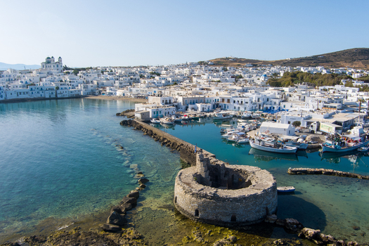 Naoussa Paros Greece 21 September 2026 Aerial view of the historic Venetian castle ruins in the harbour of Naoussa with white buildings and fishing boats in turquoise water. Naoussa Paros Greece 21 September 2026 Aerial view of the historic Venetian castle ruins in the harbour of Naoussa with white buildings and fishing boats in turquoise water.