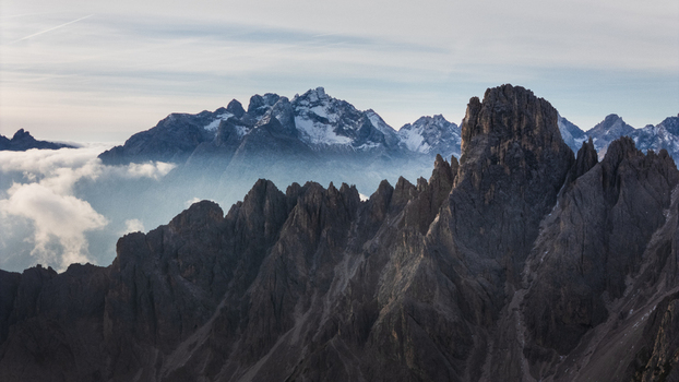 Aerial view of Cadini group mountain peaks rising above a sea of clouds under a soft sky Auronzo di Cadore Veneto Italy. Aerial view of Cadini group mountain peaks rising above a sea of clouds under a soft sky Auronzo di Cadore Veneto Italy.
