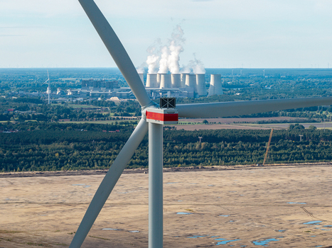 Aerial view of a wind turbine at Windpark Forst Briesnig II with the Janschwalde Power Plant emitting smoke in the background on recultivated land in Forst Brandenburg Germany. Aerial view of a wind turbine at Windpark Forst Briesnig II with the Janschwalde Power Plant emitting smoke in the background on recultivated land in Forst Brandenburg Germany.