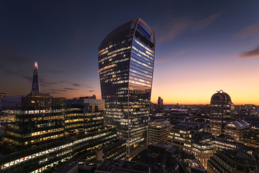 Aerial view of the London skyline at sunset featuring the illuminated Scalpel skyscraper and the Shard in the distance set against a vibrant evening sky in London England United Kingdom. Aerial view of the London skyline at sunset featuring the illuminated Scalpel skyscraper and the Shard in the distance set against a vibrant evening sky in London England United Kingdom.