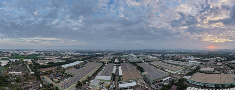 Aerial view of the industrial area in Chakan featuring large factory buildings with solar panels surrounded by greenery under a dramatic sunset sky in Chakan Maharashtra India.
