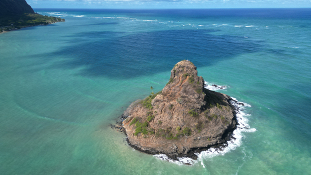 Aerial view of the stark brown islet contrasting with the turquoise waters near Kamehameha Highway Kaneohe Hawaii United States. Aerial view of the stark brown islet contrasting with the turquoise waters near Kamehameha Highway Kaneohe Hawaii United States.