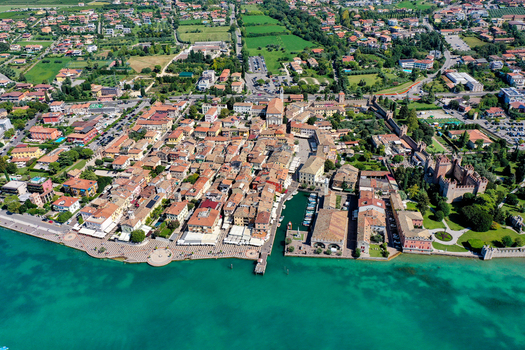 Aerial view of the historic town center with red roofed buildings a small harbor and a medieval castle on the shores of Lake Garda Italy. Aerial view of the historic town center with red roofed buildings a small harbor and a medieval castle on the shores of Lake Garda Italy.