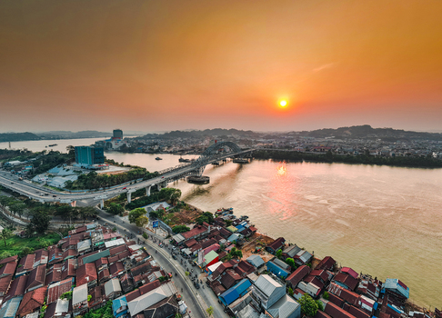 Aerial view of Jembatan Mahakam I spanning the Mahakam River at sunset with urban rooftops and golden light in Kecamatan Samarinda Seberang Kalimantan Timur Indonesia. Aerial view of Jembatan Mahakam I spanning the Mahakam River at sunset with urban rooftops and golden light in Kecamatan Samarinda Seberang Kalimantan Timur Indonesia.