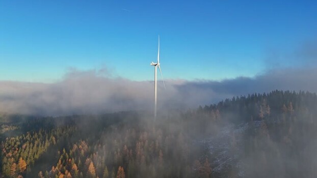 Aerial view of Windpark Freilanderalm turbine above fog Austria.