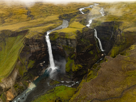 Aerial view of the majestic Haifoss waterfall plunging into a deep moss covered canyon with a winding river and misty atmosphere in Skeida og Gnupverjahreppur Iceland. Aerial view of the majestic Haifoss waterfall plunging into a deep moss covered canyon with a winding river and misty atmosphere in Skeida og Gnupverjahreppur Iceland.