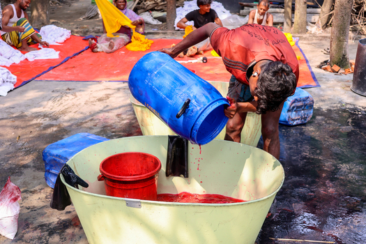 Narayanganj Bangladesh 29 March 2026 View of a worker pouring dye into a vat the red liquid contrasting against the pale container. Narayanganj Bangladesh 29 March 2026 View of a worker pouring dye into a vat the red liquid contrasting against the pale container.