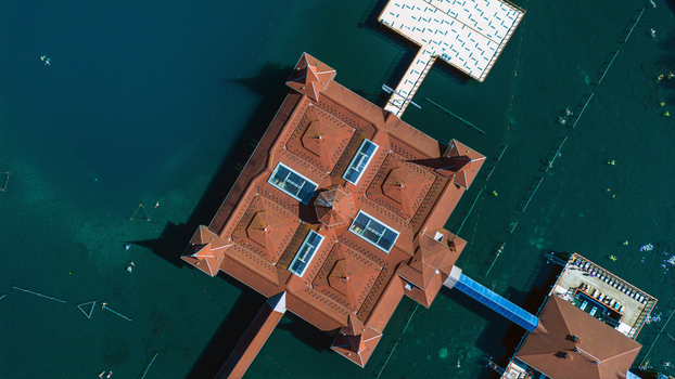 Aerial view of a building with a red roof and a bridge on the water where people swim H&eacute;v&iacute;z Zala Hungary.