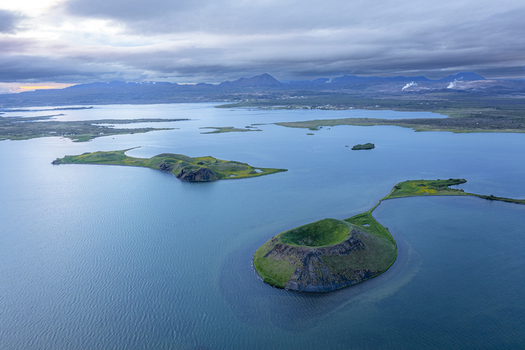 Aerial view of the volcanic pseudocraters of Lake Myvatn surrounded by blue water and green landscapes in Thingeyjarsveit Iceland.