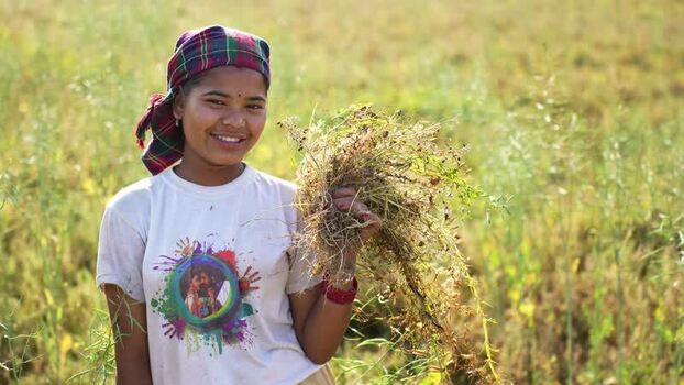 View of a smiling woman harvesting crops in a field Nepal.