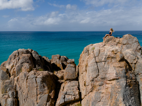 Aerial view of Castle Rock with a woman sitting on the rugged rock formation overlooking the turquoise ocean in Dunsborough Western Australia Australia. Aerial view of Castle Rock with a woman sitting on the rugged rock formation overlooking the turquoise ocean in Dunsborough Western Australia Australia.