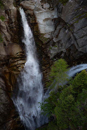 View of a waterfall cascading down rocky cliffs surrounded by pine trees in the Swiss Alps near Airolo Ticino Switzerland. View of a waterfall cascading down rocky cliffs surrounded by pine trees in the Swiss Alps near Airolo Ticino Switzerland.