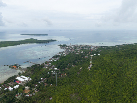 Aerial view of a coastal town nestled between lush green hills and turquoise waters Karimunjawa Central Java Indonesia.