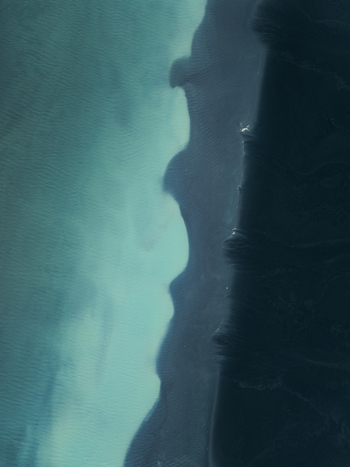 Aerial view of the dramatic contrast between the dark black sand beach and the vibrant turquoise waters of the Atlantic Ocean along the coast of Iceland. Aerial view of the dramatic contrast between the dark black sand beach and the vibrant turquoise waters of the Atlantic Ocean along the coast of Iceland.