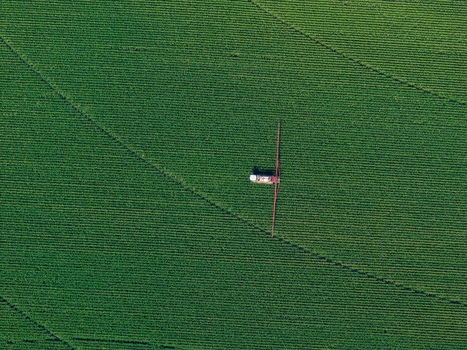 Aerial view of a tractor spraying a large green agricultural field in Hombourg Grand Est France. Aerial view of a tractor spraying a large green agricultural field in Hombourg Grand Est France.
