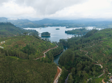 Aerial view of the lush green hills and tea plantations surrounding the calm waters of Castlereagh Reservoir with a winding road in Nallathanniya Central Province Sri Lanka. Aerial view of the lush green hills and tea plantations surrounding the calm waters of Castlereagh Reservoir with a winding road in Nallathanniya Central Province Sri Lanka.